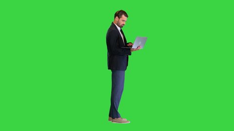 Young standing business man working on a laptop on a Green Screen, Chroma Key.