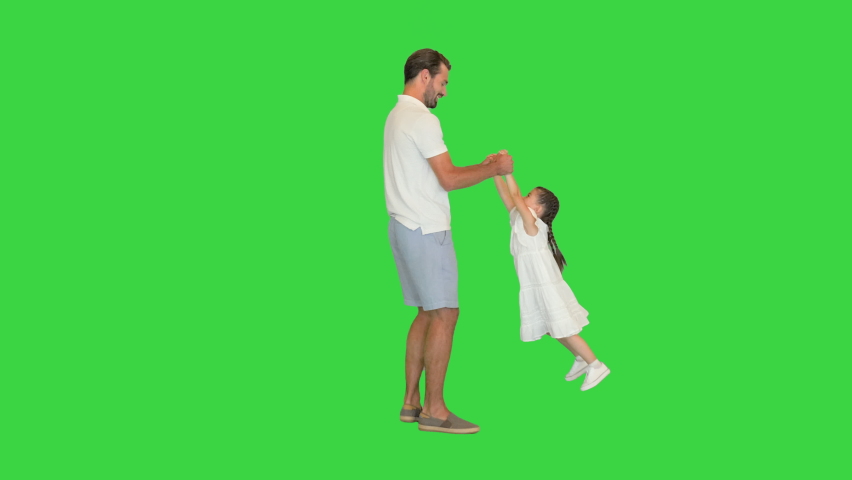 Happy father holding his daughter's hands and spinning around letting her fly on a Green Screen, Chroma Key.