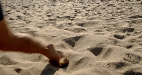 Football soccer game on the beach. Male feet leading the ball on the sandy sea beach, 4k slow motion
