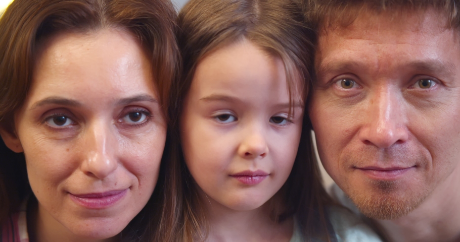 Close up portrait of happy smiling mother, father and little daughter. Headshot of loving young parents and preteen girl child looking at camera posing together | Shutterstock HD Video #1067697536