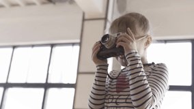 A young girl learns to take pictures on the old fashioned camera. Action. Little girl holding camera in a photo or video studio.