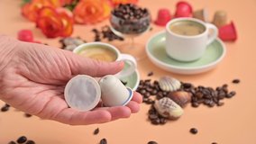Capsules for an espresso machine in hand. Aromatic Italian coffee with beautiful crema. Arabica coffee beans for the preparation of a traditional drink. High quality FullHD footage