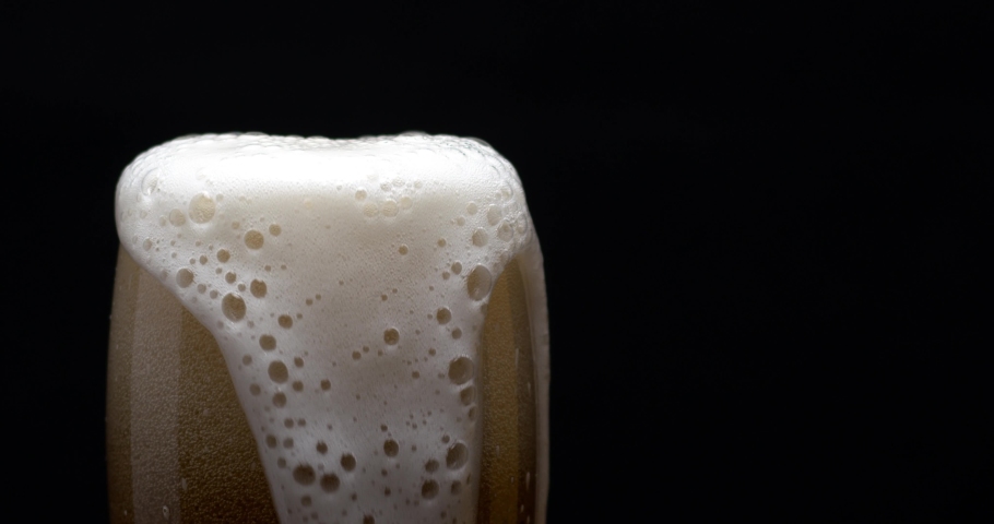 Light beer is pouring into glass. Cold Beer in a glass with water drops. Craft Beer forming foam close up. Freshness and froth. Isolated black background. Microbrewery craft beer. | Shutterstock HD Video #1067701409