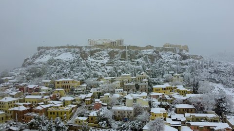The old town Plaka with Monastiraki Square and Parthenon Temple at the Acropolis of Athens, Greece, during a winter day with heavy snow and ice