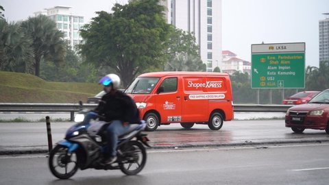 Shah Alam Selangor, Malaysia - February 19, 2021 : Selective focus of Shopee Express courier van moving on a rainy slippery road. 