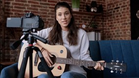 Distance education. Guitarist-girl making video lessons and tutorials for internet vlog website classes. Female musician is recording video with camera playing the guitar. Blogging and music concept.