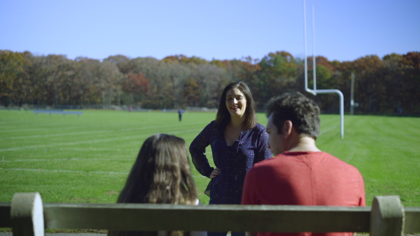 Young Family Outdoors at a Football Field and Autumn Trees in the Background