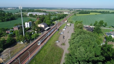 Passenger train departure from the railway station. A small town among green fields and meadows. A freight train in the background
