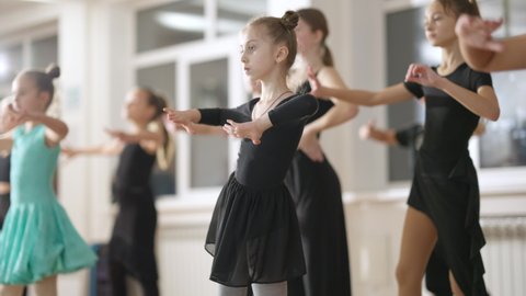 Group of confident children training latin dance in dancing school. Talented Caucasian girls and boys rehearsing in dance studio moving in slow motion. Skill and art concept.