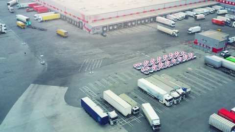 Logistics park with loading hub. Semi-trailers trucks stand at warehouse parking lot and wait for load and unload goods at ramps. Aerial view 