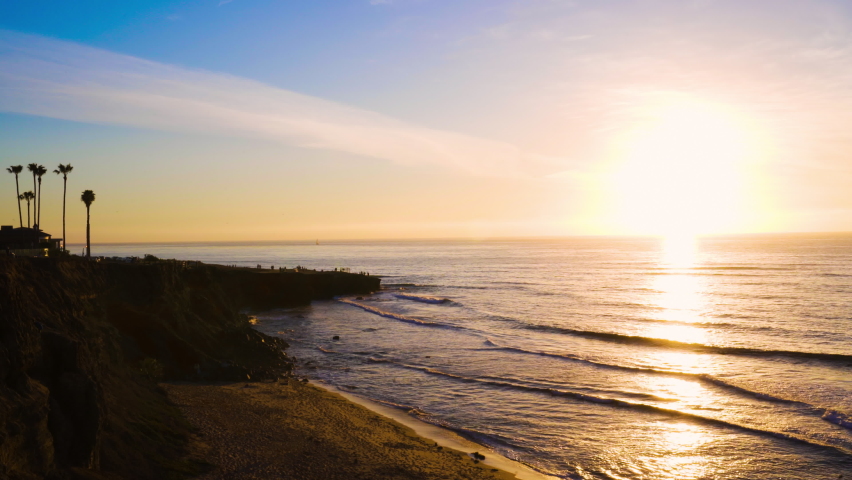 Tracking bright and colorful picturesque sunset over Pacific ocean along coastline cliffs in San Diego, CA 