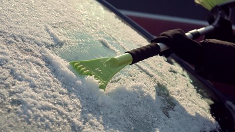 Scratching Ice From Car Window In Winter.Brushing Snow And Ice From Car Glass.Female Cleaning Fresh Snow After Snowstorm From Vehicle.Sweep Snow From Automobile With Brushes In Winter.Scraping Ice 