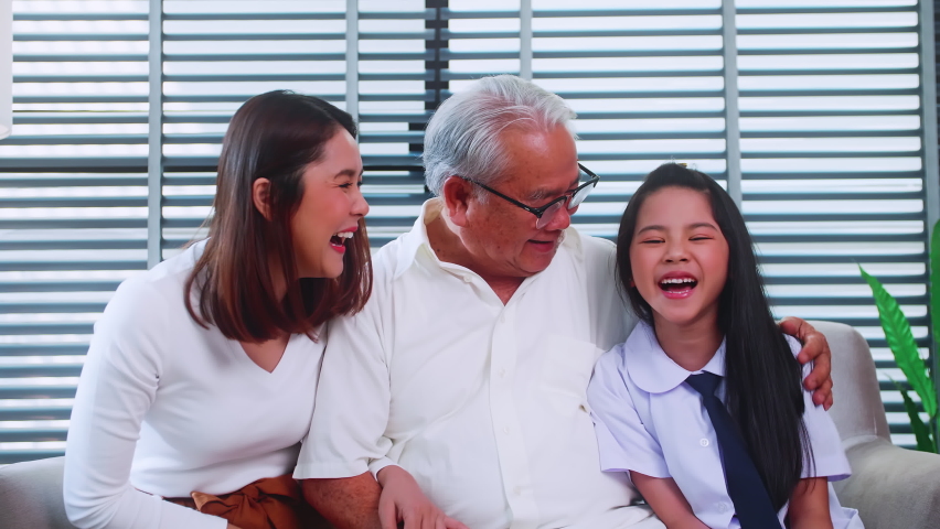Happy family with grandfather, mother and little daughter spending time together in living room.