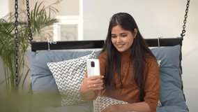 Portrait of attractive young Asian girl having a video chat talking smiling with friends,family.Selfie chat smartphone call.Close-up of young woman talking through video chat using cellphone outdoors.