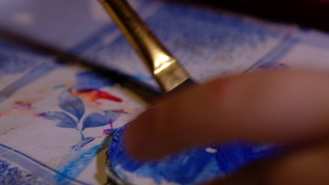 Close up of the little hand of a kid painting with watercolors