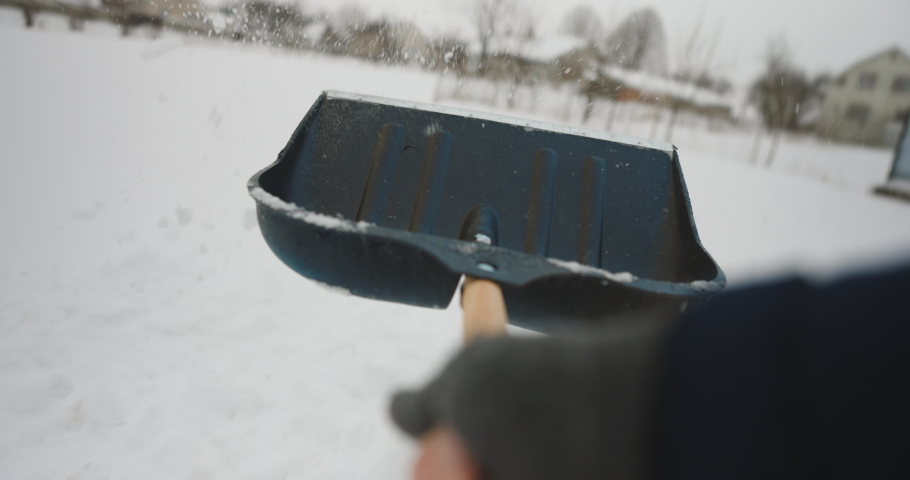 Man with a shovel removes snow. Cleaning the area near the house after a snowstorm. Person shoveling snow out of the driveway. Huge snow drifts. Difficult situation in the city after a snow storm. Royalty-Free Stock Footage #1067751767