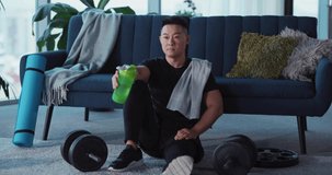 Zoom Portrait of Chinese Young Bodybuilder Sportsman Drinking Water Refreshing after Intense Exercising Workout at Home.