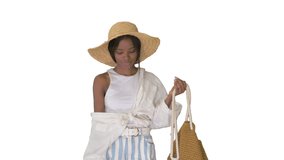 Relaxed african american girl walking wearing a straw hat and a bag on white background.