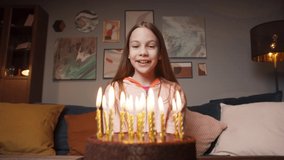 Children kid girl blow out candles on birthday cake, celebrating birthday together at home, video camera view of blowing candle and making wish