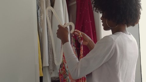Beautiful black woman with afro choosing clothing from her wardrobe