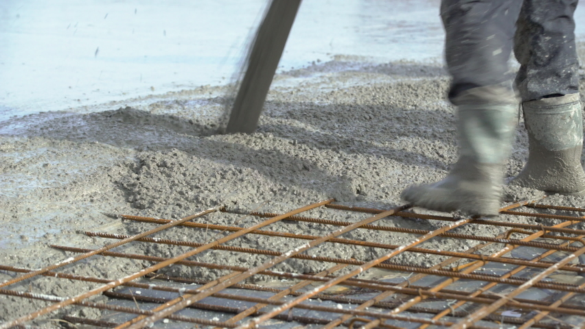 Concreting of reinforced concrete slab. Worker concretes foundation, rebar, pour cement mortar on reinforcing mesh or cage from pump concrete mixer. Builders are building a factory, hangar, house Royalty-Free Stock Footage #1067765384