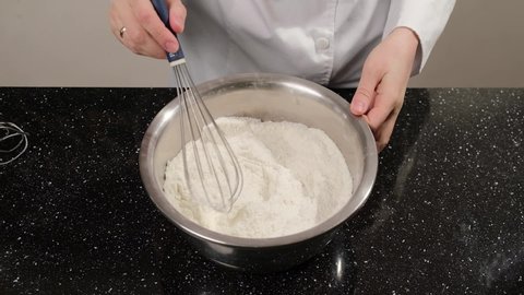 Close up of a woman hands that whisk almond flour in the bowl, preparing dough for macarons.