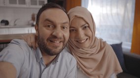While Muslim husband and wife make video calls with their families on the phone, they give them the baby news by showing the ultrasound photo. Baby news concept. Slow motion video. Frontal camera wiev