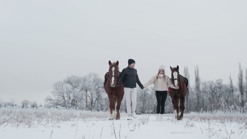 Couple in love with horses in winter forest 4K. Romantic walk