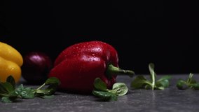 Ripe red and yellow peppers with water drops on black background