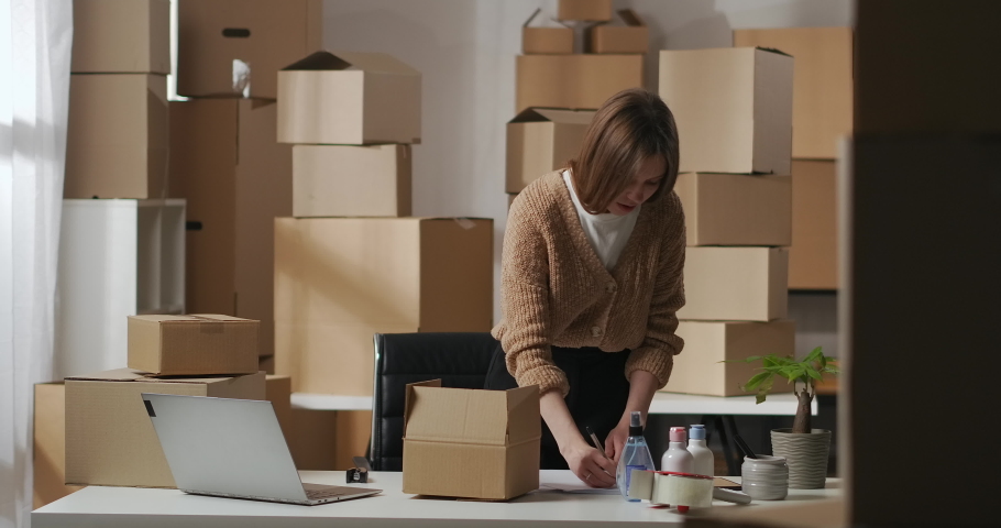 woman is packaging order with handmade cosmetics in cardboard box in small home warehouse, business and entrepreneurship Royalty-Free Stock Footage #1067772674