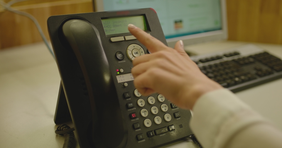 4K Close-up hand of woman pushing  the  button of the  black landline phone and answers. Call center. Operator picking up the phone for answering  the questions. Office room. Customer support center. 