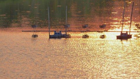 beautiful silhouette scene of sunset reflection on water wave surface with paddle wheel or aeration machine in shrimp farm