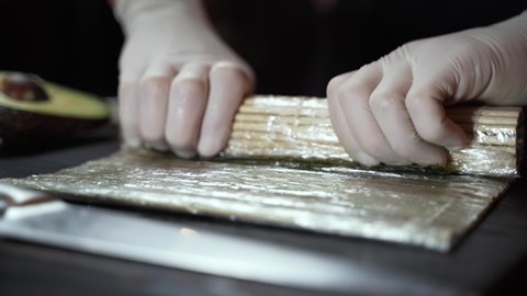 Chef in white gloves prepares sushi