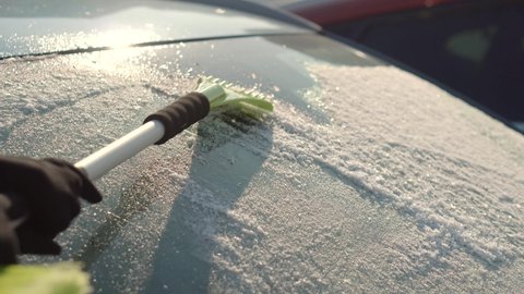 Female Cleaning Fresh Snow After Snowstorm From Vehicle.Sweep Snow From Automobile With Brushes In Winter.Scraping Ice. Scratching Ice From Car Window In Winter.Brushing Snow And Ice From Car Glass.