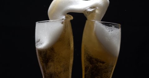 Super slow motion of two beer glasses hitting together, cheers concept. Having a toast with two glasses of beer and spilling. Shot with high speed camera.