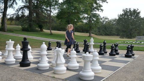 Little girl is playing large outside chess in the park. Active child, happy childhood concepts
