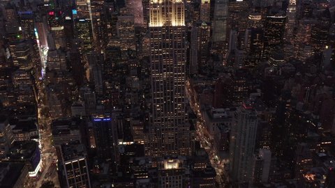 Slow tilt up revealing Empire State Building in Manhattan at Night surrounded by Skyscrapers in Big City Skyline, Aerial View forward, Manhattan, New York City in 2019