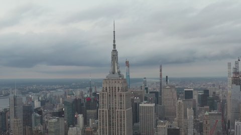 Aerial view closing in on the top of the Empire State Building in Manhattan, New York city with tall skyscrapers and Central Park in the background in 2019