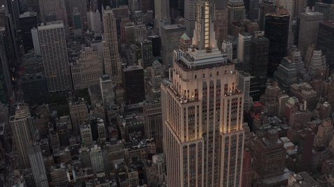 Aerial view flying away from the Empire State Building in the evening lights with skyscrapers and office buildings in the background, Manhattan, New York City in 2019