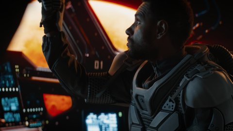 Portrait of African American Black male astronaut adjusting controls inside spaceship cockpit. Sci-fi space exploration concept. Mars mission. Shot with 2x anamorphic lens