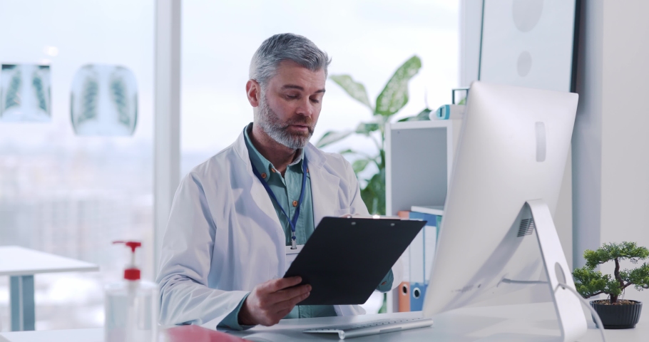 Experienced doctor therapist communicating remotely with online patient customer explaining diagnosis giving advice prescriving medications. Hospital office. Royalty-Free Stock Footage #1067817317