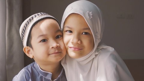 Closed up shot of Asian Muslim kids.young sister and brother sibling in Muslim traditional dress.Happy and looking to camera.Concept of happy kid in Ramadan or family bonding.