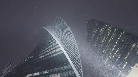 Bottom view of Moscow city towers in snowy cold weather. Action. High skyscrapers with glass windows late in winter evening.