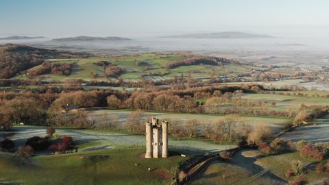 Aerial drone video of Broadway Tower, a famous iconic tourist attraction in The Cotswolds Hills, iconic English landmark with beautiful misty British countryside scenery, Gloucestershire, England, UK