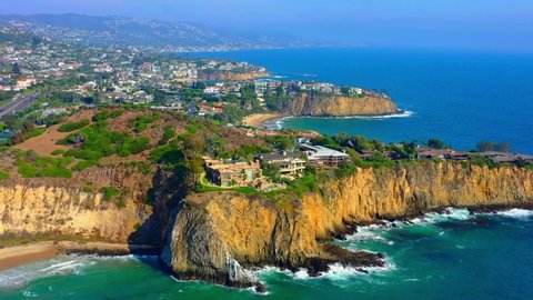 Huge houses on a cliff in Laguna Beach Ca. This drone clip shows the beach, sand, and beautiful water in Southern California.