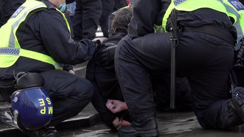 London , United Kingdom (UK) - 12 19 2020: Police officers detain man in handcuffs on a wet pavement