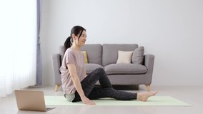 sporty asian woman stretching in the living room