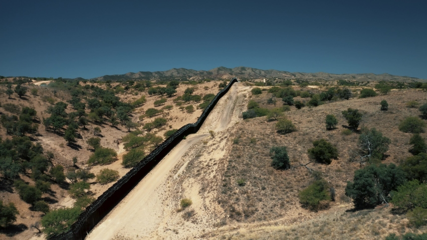Aerial view of Nogales border area showing border fence separating the United States of America and Mexico with U.S. Border and Customs Protection patrolling border area with their vehicles | Shutterstock HD Video #1067832716