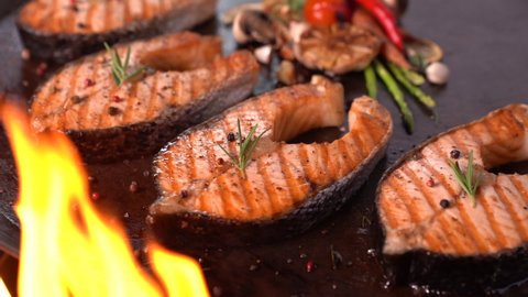 Grilled salmon fish with various vegetables on pan on the flaming grill