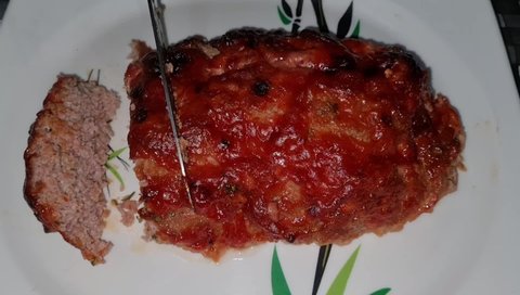 Cutting of a  steamy hot mouthwatering tempting freshly baked meatloaf and making it sliced.